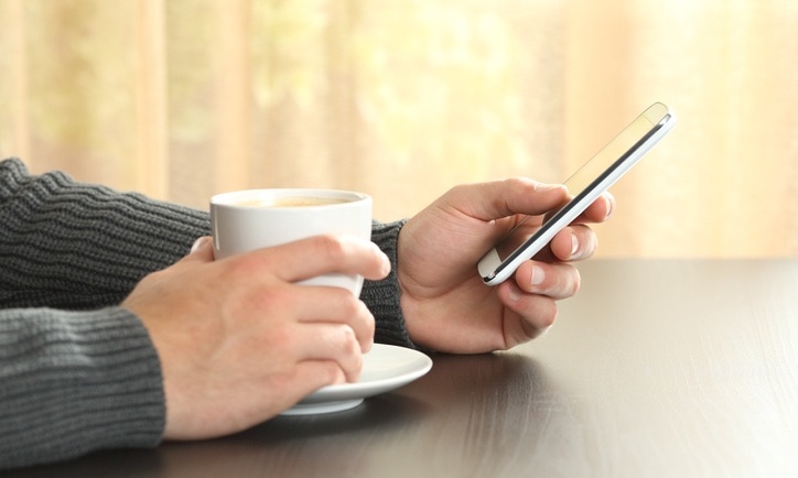 Checking_phone_while_holiding_coffee_securitypage