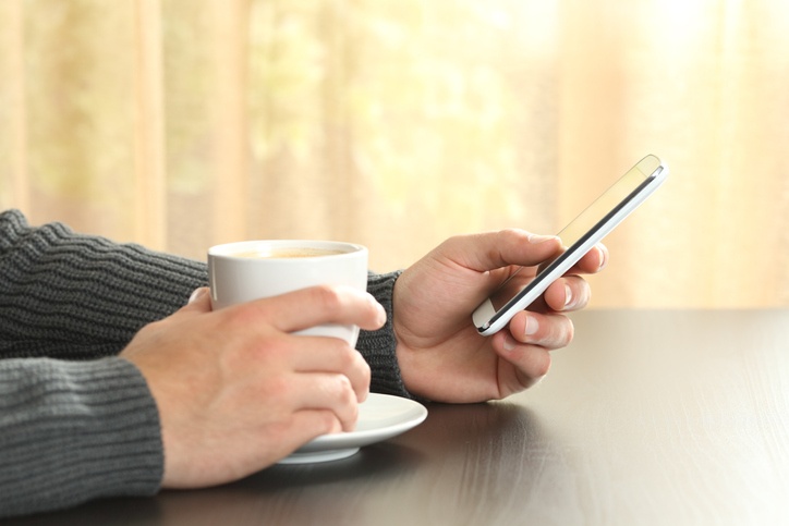 Checking_phone_while_holiding_coffee